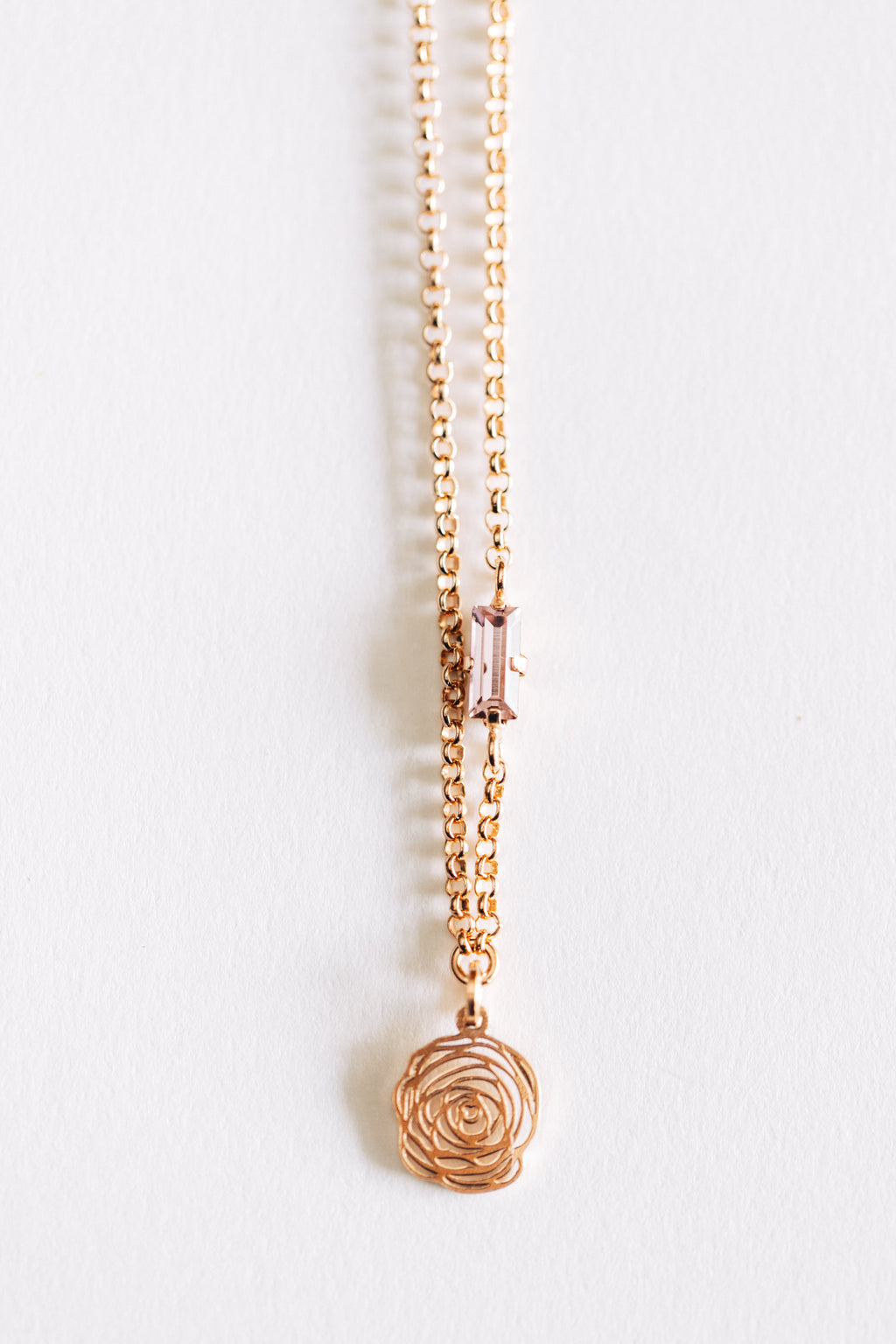 A hypoallergenic rose gold necklace with a small rose design pendant, displayed against a white background.