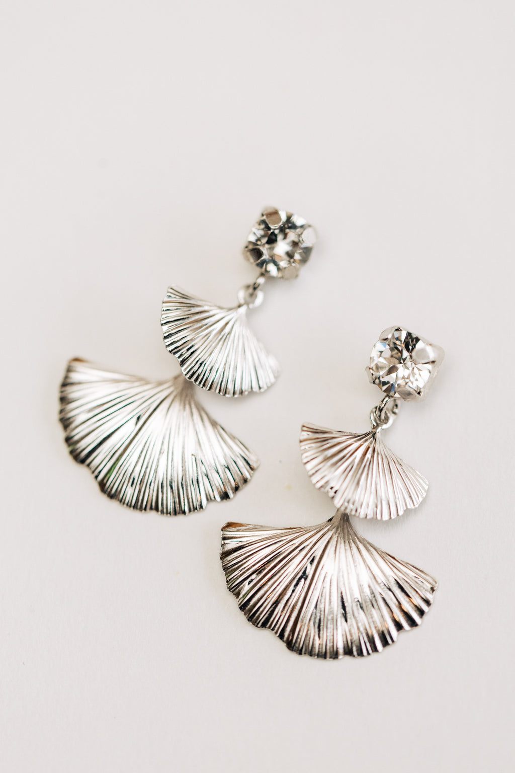 Silver fan-shaped earrings with crystal accents on a light background