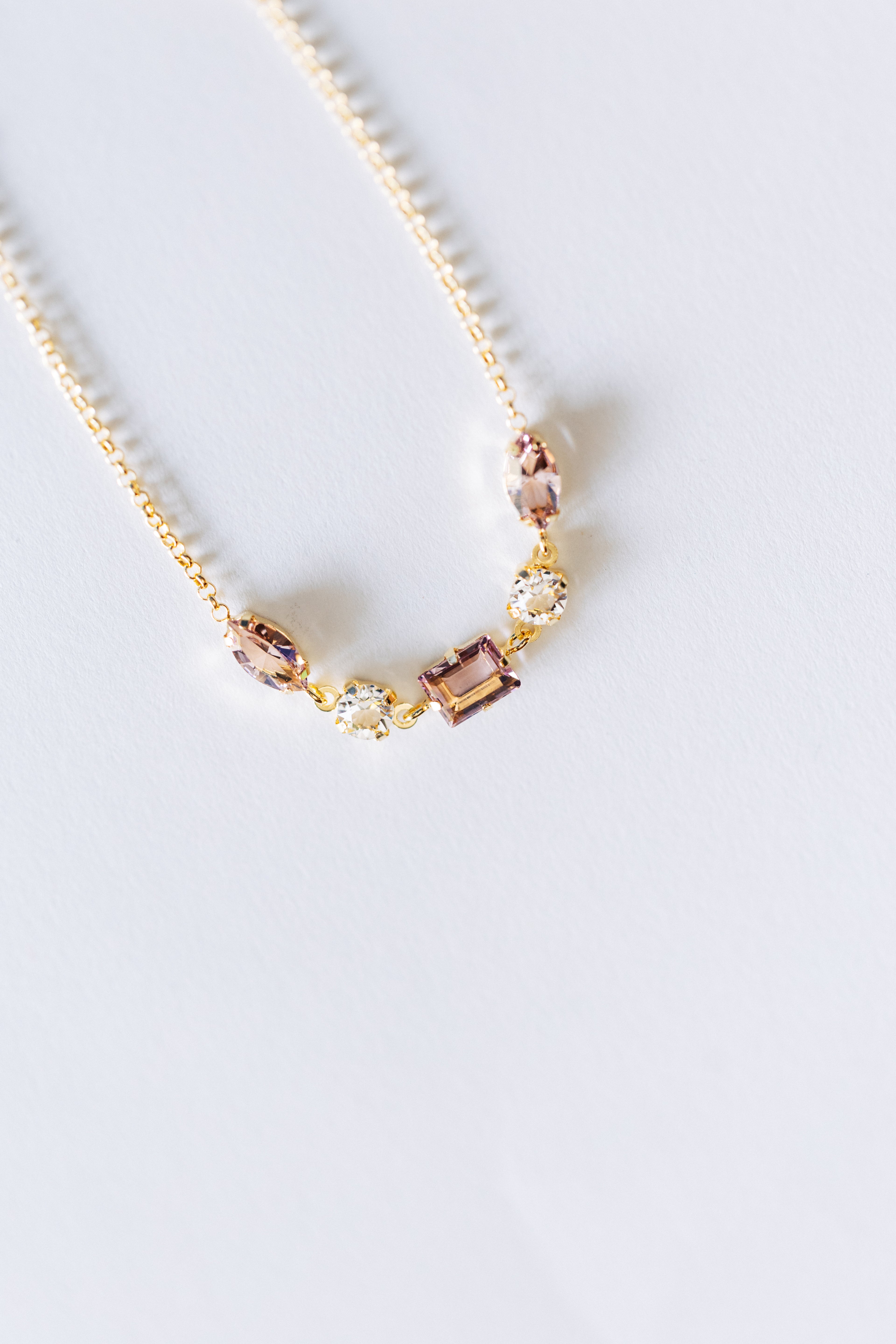 A rose gold bracelet with small clear crystals set on a white surface.