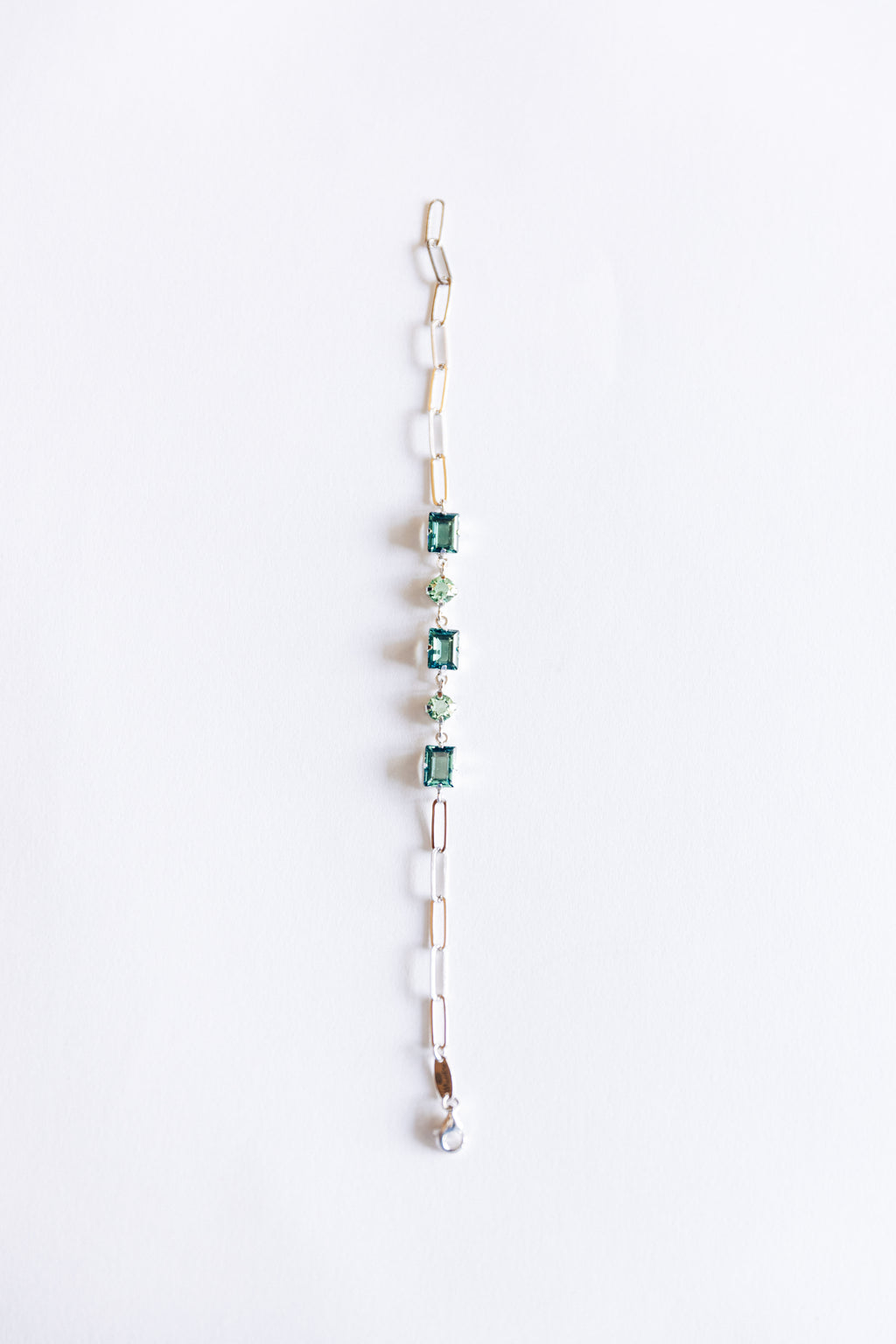 Silver link bracelet with green crystalson a white background