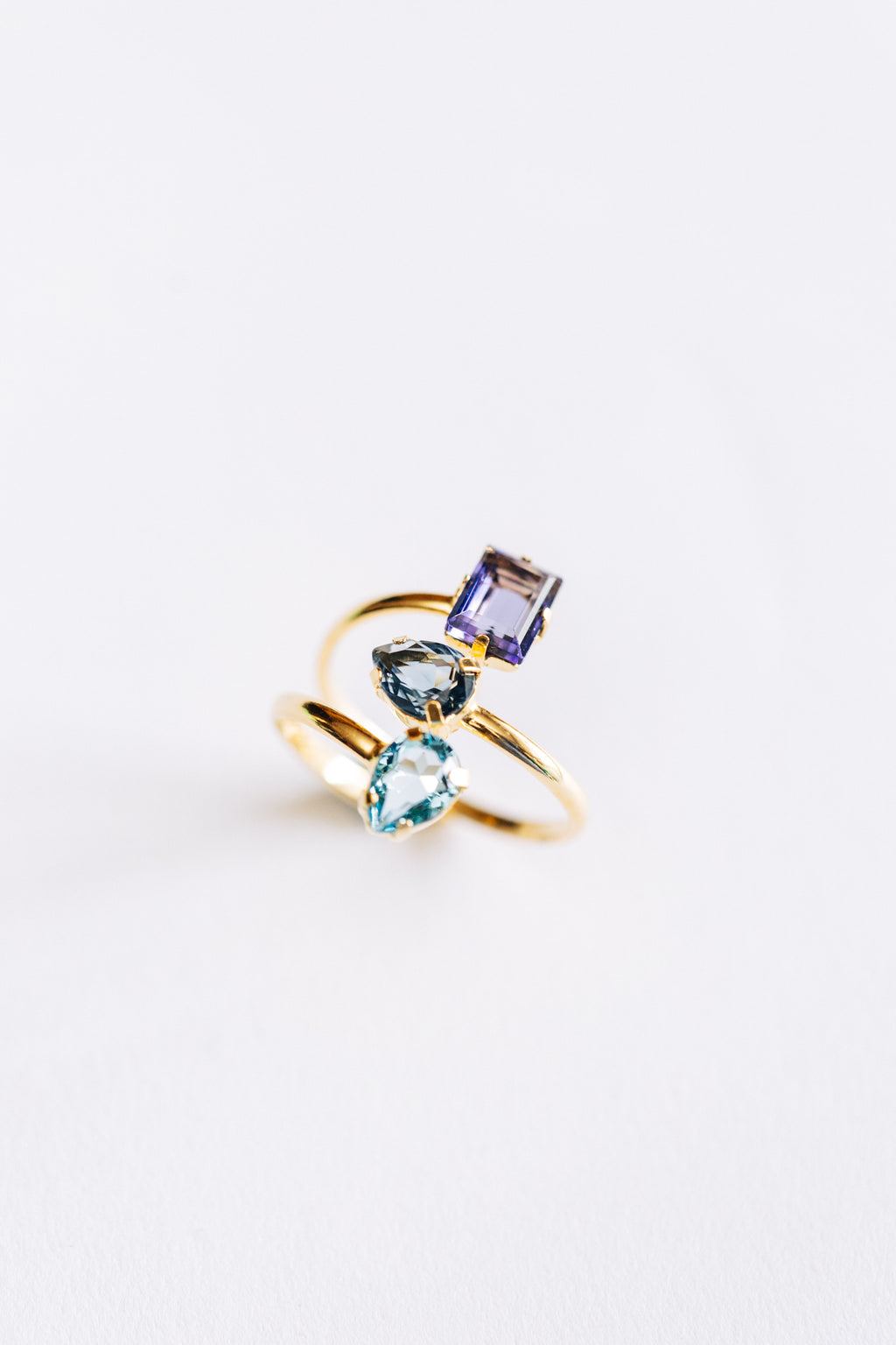 A hypoallergenic gold ring with three crystals on a white background