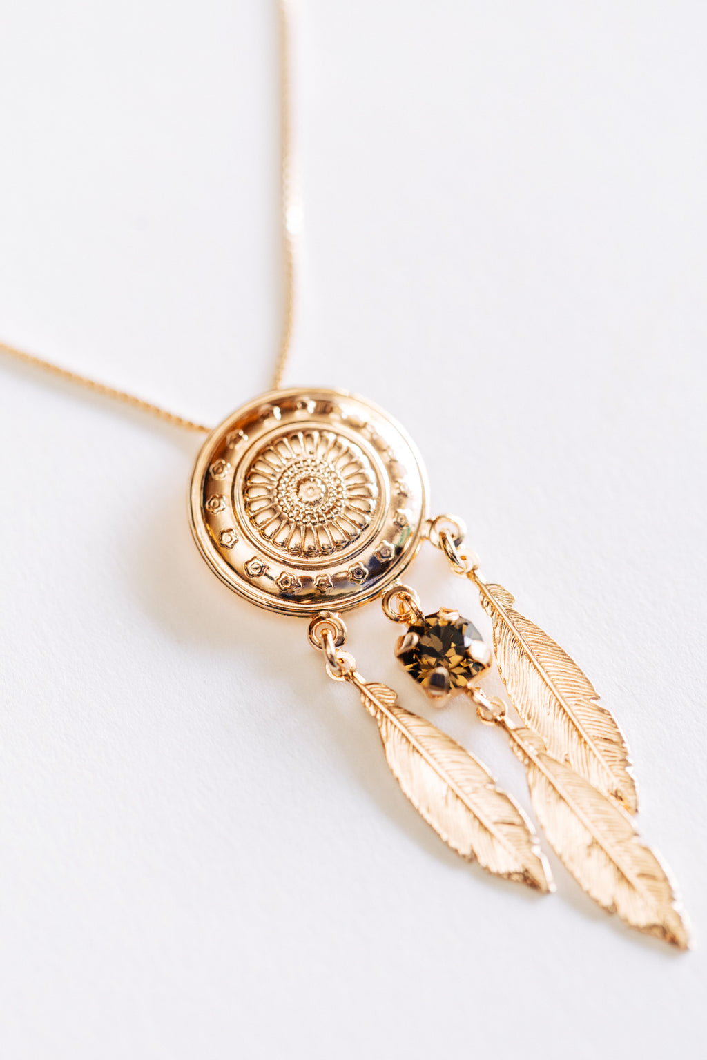 A hypoallergenic rose gold necklace with a round pendant featuring a dreamcatcher design