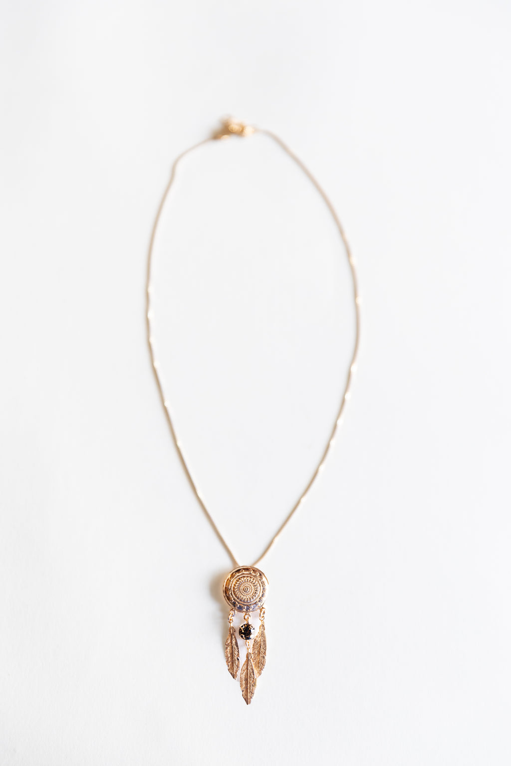 Necklace with a feather and circular pendant on a white background