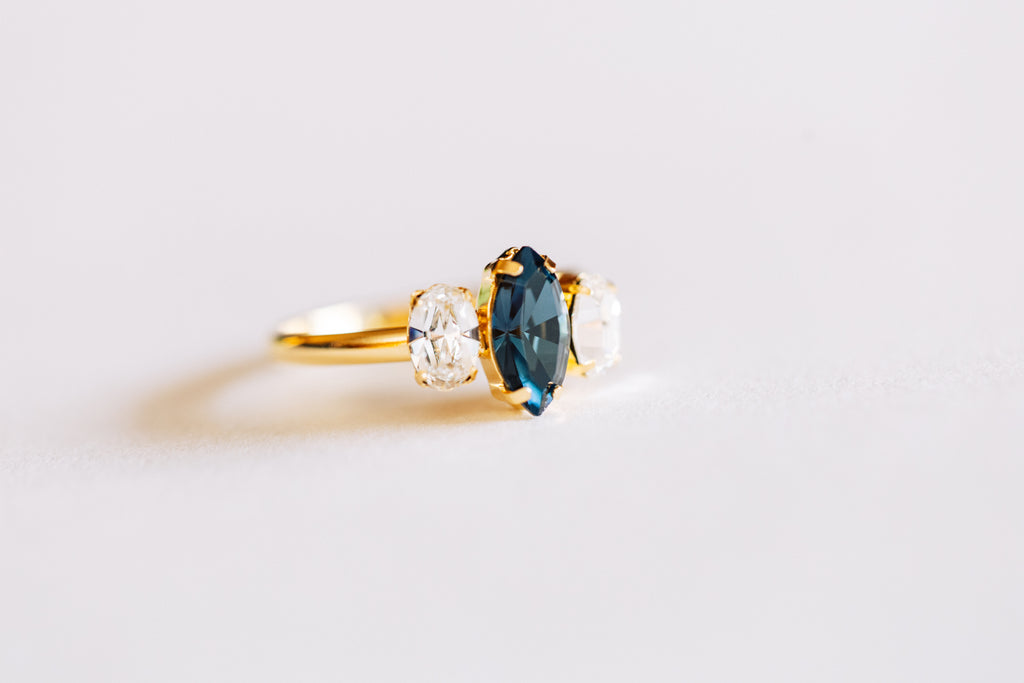 Gold ring with blue crystal on a light background
